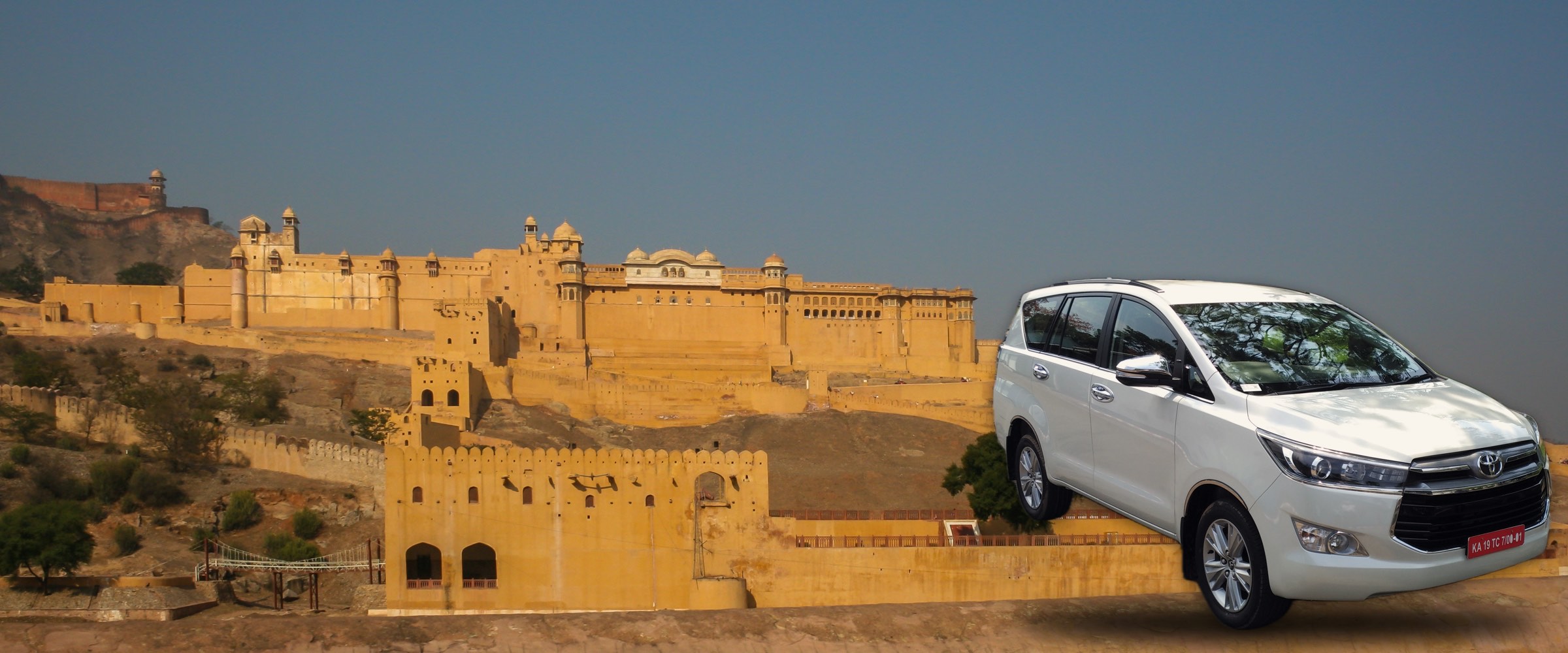 A white Toyota Innova Crysta in front of Amber Fort, Jaipur, at dusk